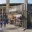 Foto Ein dunkelgrauer Merchandising-Container in Doppelstock-Optik, konfiguriert als „Stadium Cap Shop“ vor dem Berliner Olympiastadion, mit Fans und Verkaufspersonal an der Theke.